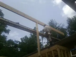 Carpenter setting a ridge beam over a new addition frame — Ice Dam Removal by Roofing Brothers in Cedar Valley