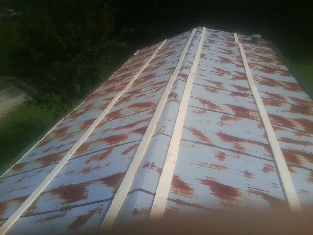 Rusted metal roof panels with new wood purlins before replacement — Storm Damage Roof Repair in Cedar Valley by Roofing Brothers