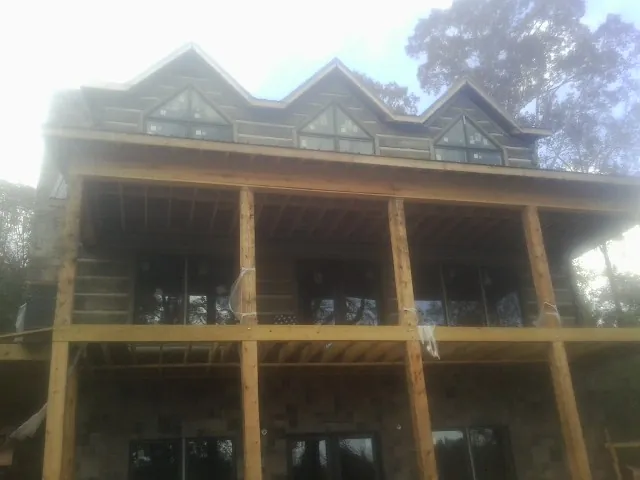 Dormers and porch framing on a large log home under construction — Roof Coating work by our crew in Cedar Valley