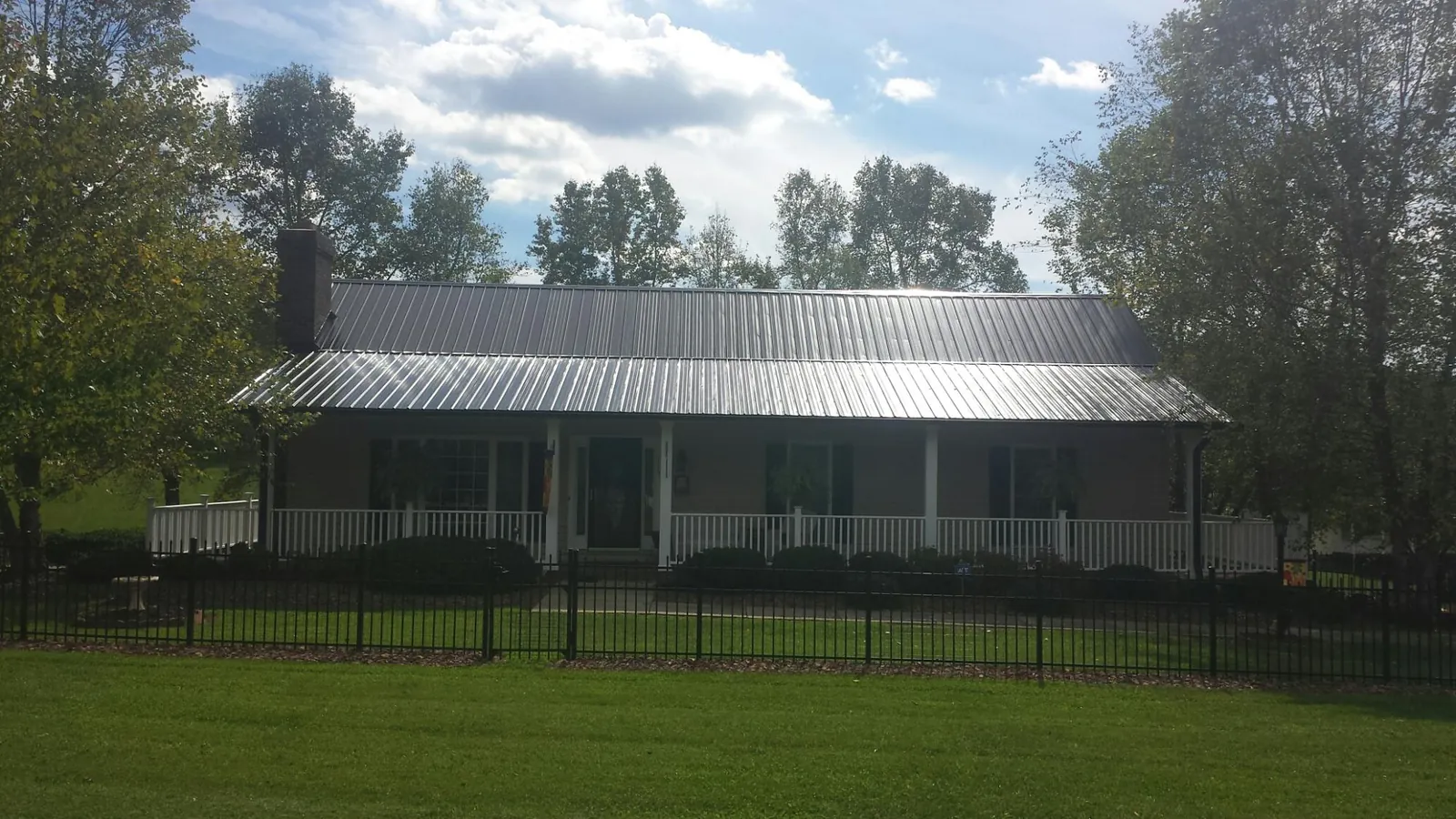 Gray metal roof on a brick ranch with a full width front porch — Gutter Guard Installation work by our crew in Cedar Valley
